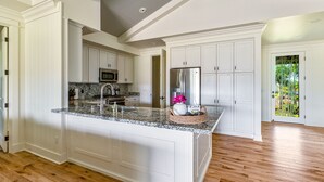 A spacious kitchen with white cabinetry, granite countertops, and a large island.