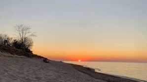 Una spiaggia al tramonto, con sabbia fine e vegetazione rada.