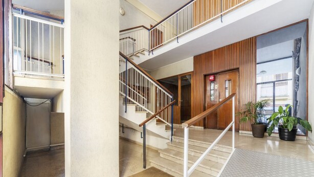 Ein mehrgeschossiges Interieur mit einer Treppe, einer Holztür und Topfpflanzen.
