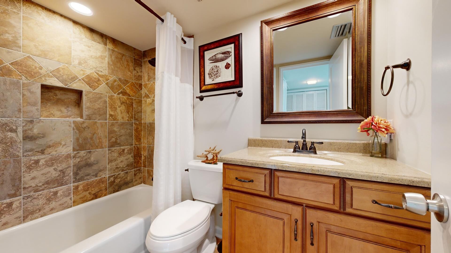 A bathroom with a bathtub, toilet, vanity with a sink, and a mirror.