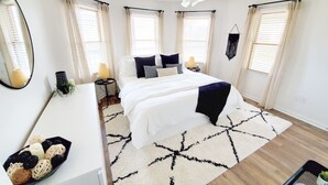 A bedroom with a bed, bedside tables, a ceiling fan, and a large mirror. - OBX Beach's, Natural Light, Roof Deck, Huge Home! (Kitty Hawk)