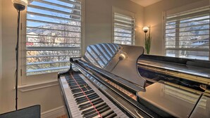 A grand piano in a room with large windows, a standing lamp, and a view of a snowy mountain. - Mountain-View Home < 15 Mi to Alta + Snowbird (Sandy)