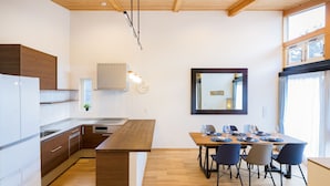 A modern kitchen with wooden cabinets, a built-in oven, and a dining area with a wooden table and chairs.