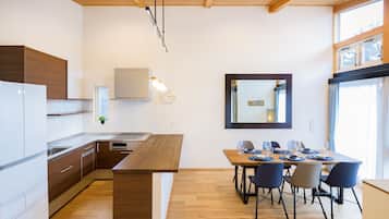 A modern kitchen with wooden cabinets, a built-in oven, and a dining area with a wooden table and chairs.