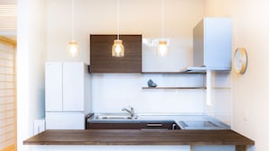 A modern kitchen with a wooden countertop, white cabinets, and pendant lights.