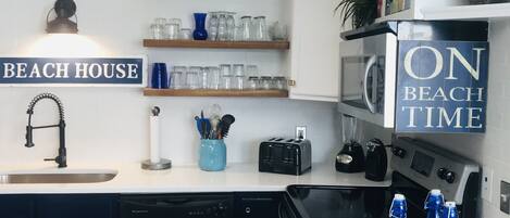 Una cocina moderna con pileta, lavavajillas, tostadora, licuadora y un cartel que dice "BEACH HOUSE".