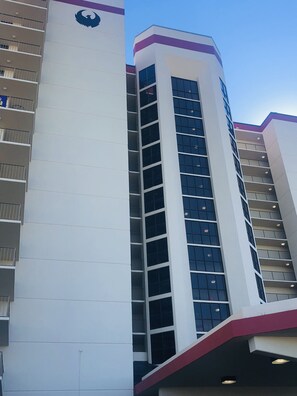 A multi-story building with a white facade and a purple accent.