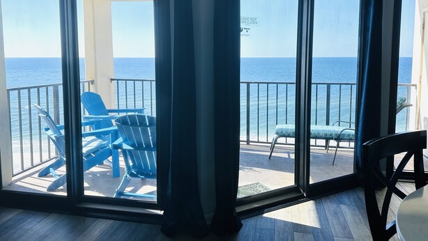 Une pièce dotée d’une grande porte-fenêtre coulissante donnant sur un balcon avec des chaises bleues et une table.