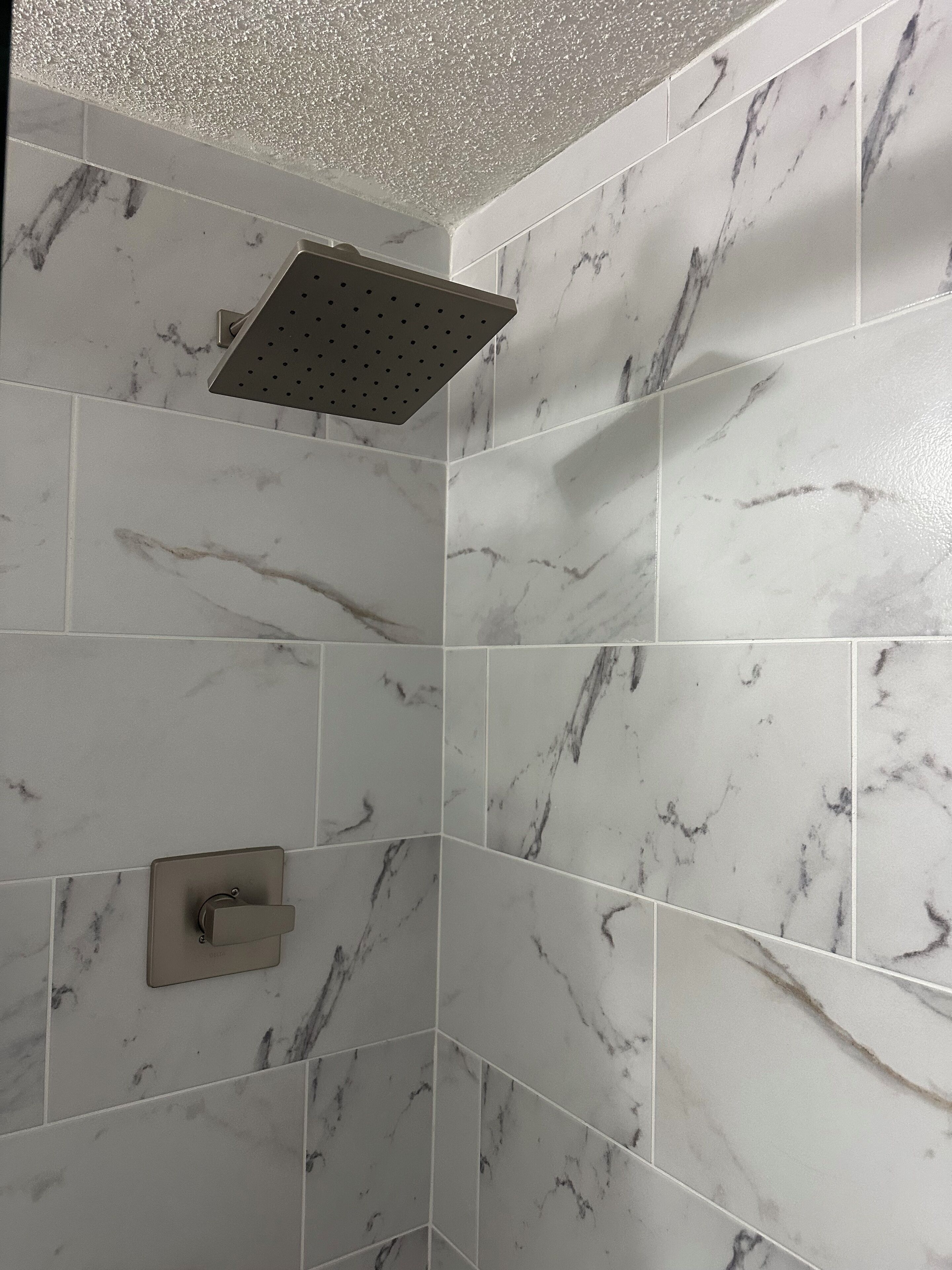 Zona de ducha con ducha de techo y panel de control en la pared.