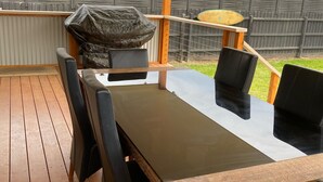 Un patio techado al aire libre con una mesa y cuatro sillas.