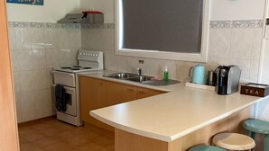 Una cocina compacta con estufa, lavamanos y cafetera.