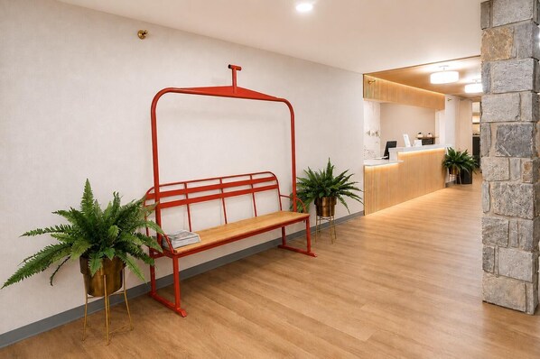 A reception area with a wooden bench, potted plants, and a reception desk.
