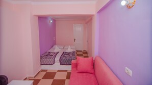 A room with a checkered floor, a pink sofa, and a bed with patterned bedding. - Best location (Dahab)