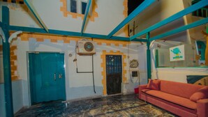 A room with a blue door, a red couch, and a wall-mounted air conditioner. - Best location (Dahab)