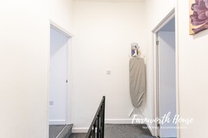 Stroll through the hallway of Farmland House, featuring a simple design with a carpeted floor and a coat rack for your belongings.