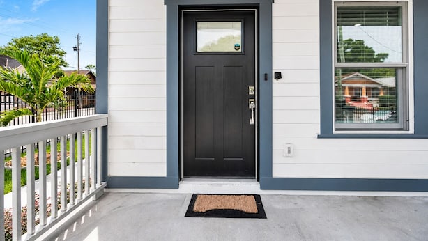 A residential building with a black front door, a mailbox, and a window with a view of a house. - Ybor City Group Home, Sleeps 12 | Emperor Castle: Game Room & Parking (Tampa)
