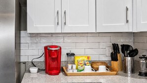A kitchen with white cabinets, a red coffee maker, a wooden tray with tea bags, and a knife block. - Ybor City Group Home, Sleeps 12 | Emperor Castle: Game Room & Parking (Tampa)