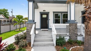 A two-story house with a front porch, a black door, and a mailbox. - Ybor City Group Home, Sleeps 12 | Emperor Castle: Game Room & Parking (Tampa)