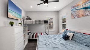 A bedroom with a bunk bed, a single bed, a ceiling fan, and artwork on the walls. - Ybor City Group Home, Sleeps 12 | Emperor Castle: Game Room & Parking (Tampa)