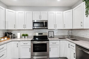 A modern kitchen with white cabinets, stainless steel appliances, and a granite countertop.