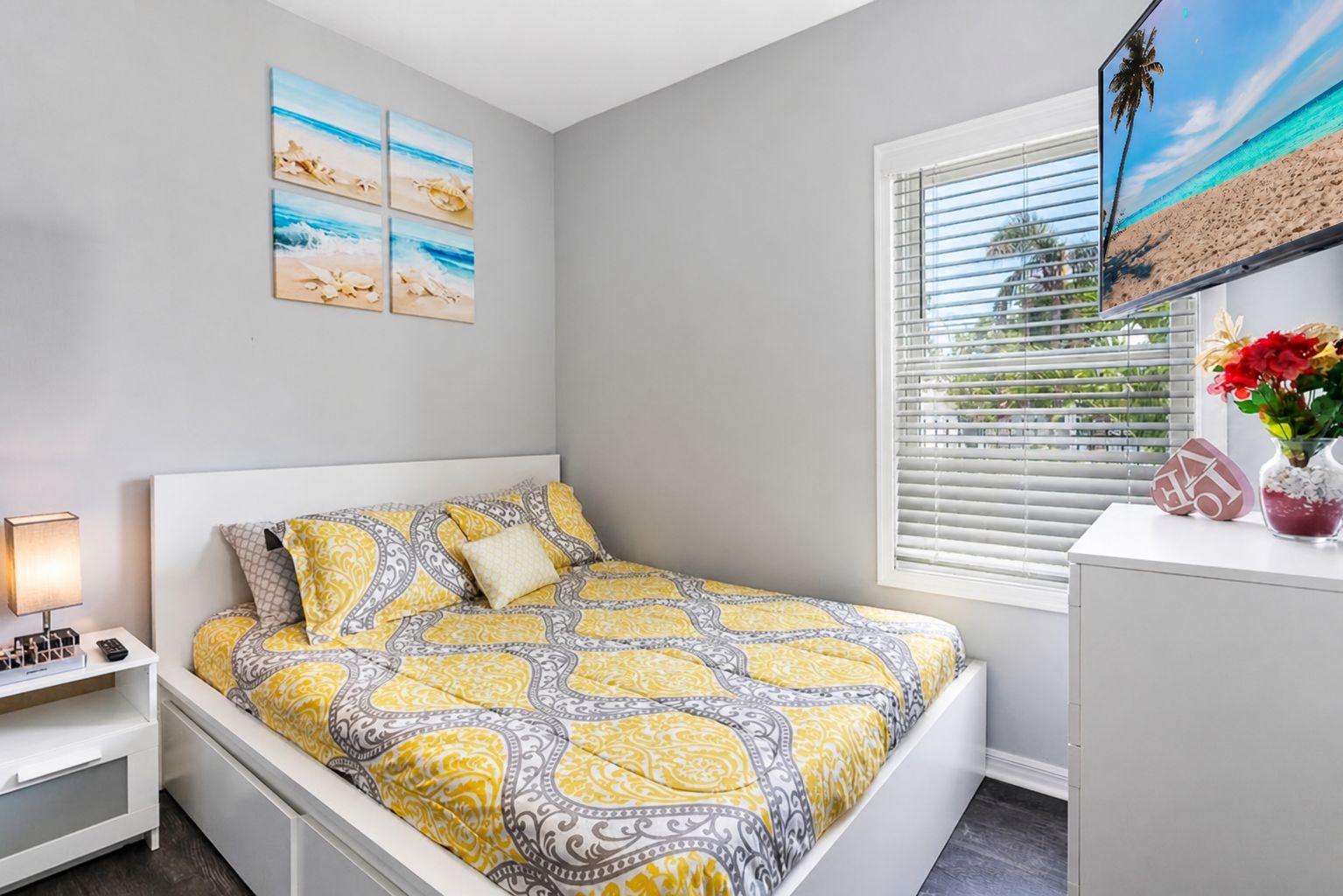 A bedroom with a bed, bedside table, lamp, and artwork on the wall.