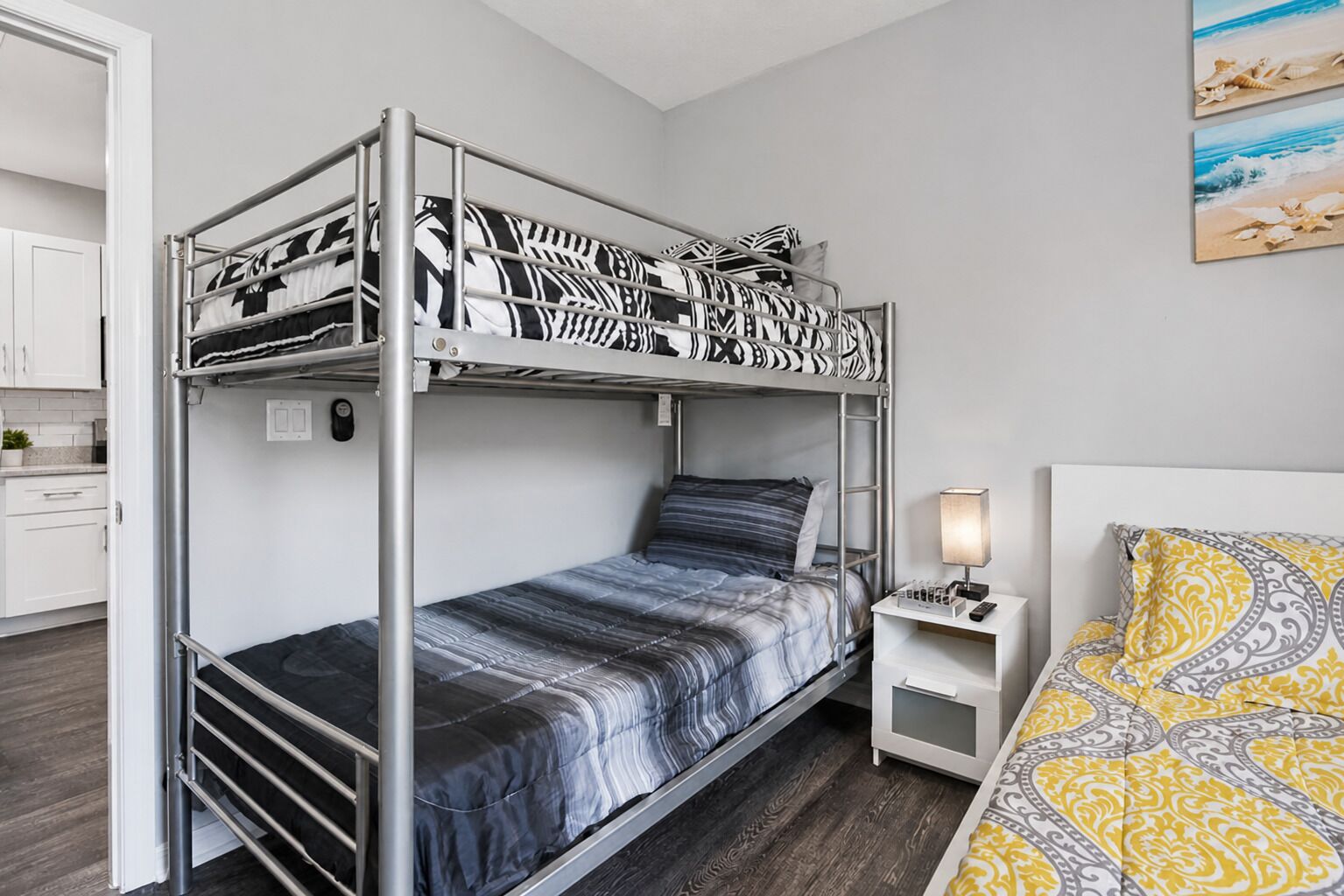 A bunk bed with a desk and chair, a bedside lamp, and a bed with patterned bedding.