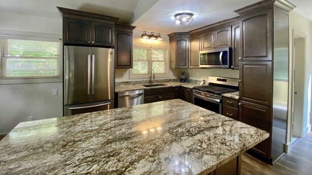Una cocina moderna con gabinetes de madera oscura, electrodomésticos de acero inoxidable y encimera de granito.