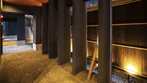 A modern interior with concrete pillars, a wooden wall, and a gravel floor. - HALE Kyoto Toji (Kyoto)