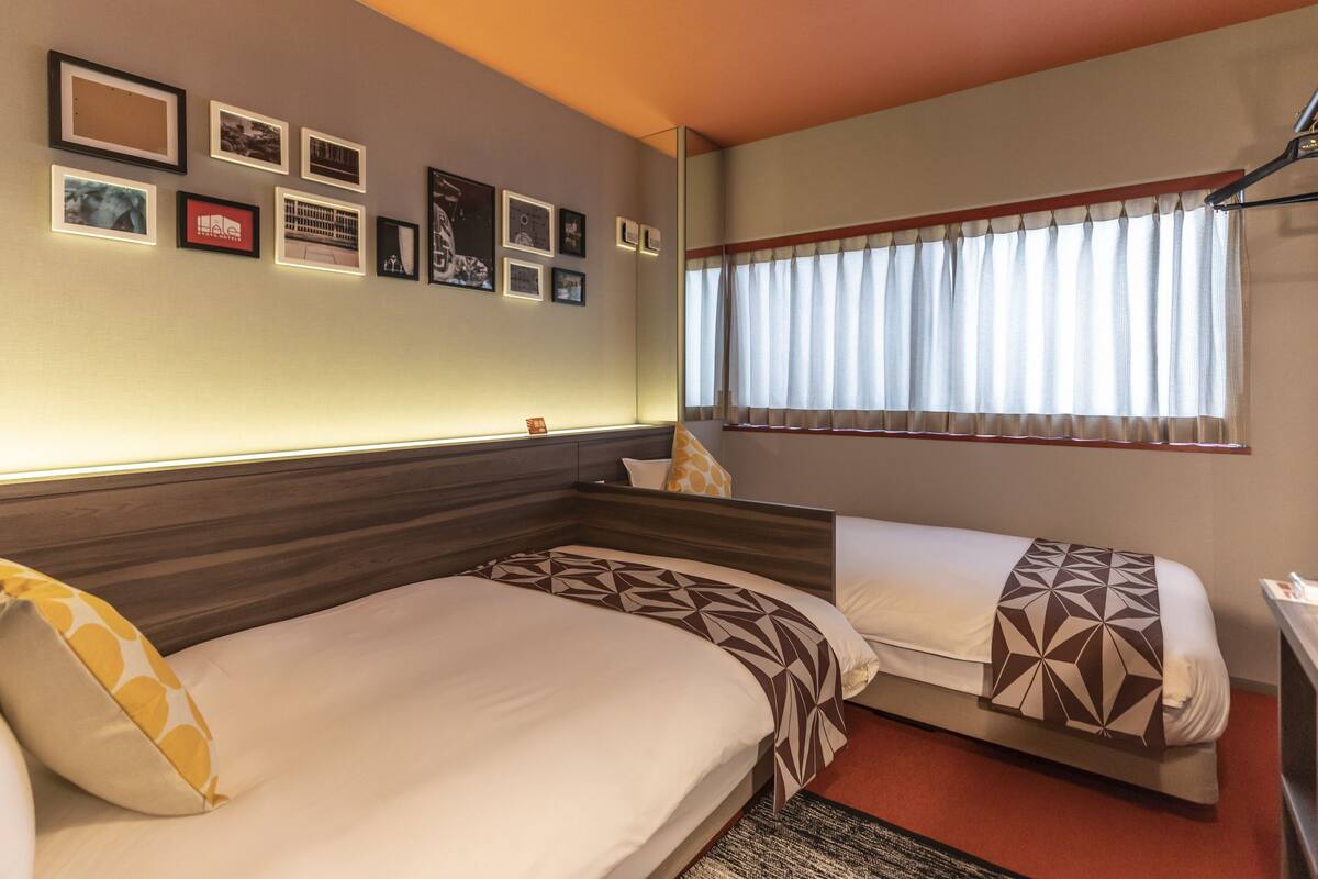A hotel room with two beds, a large mirror, and a wall adorned with framed pictures.