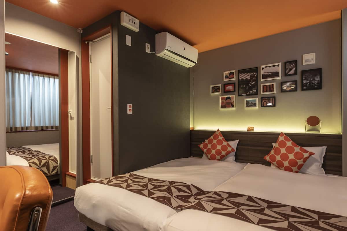 A hotel room with a large bed, a desk, a chair, and a wall with framed pictures.
