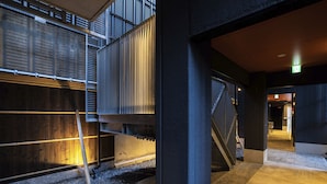 A modern building with a concrete exterior, metal railings, and a gravel ground. - HALE Kyoto Toji (Kyoto)
