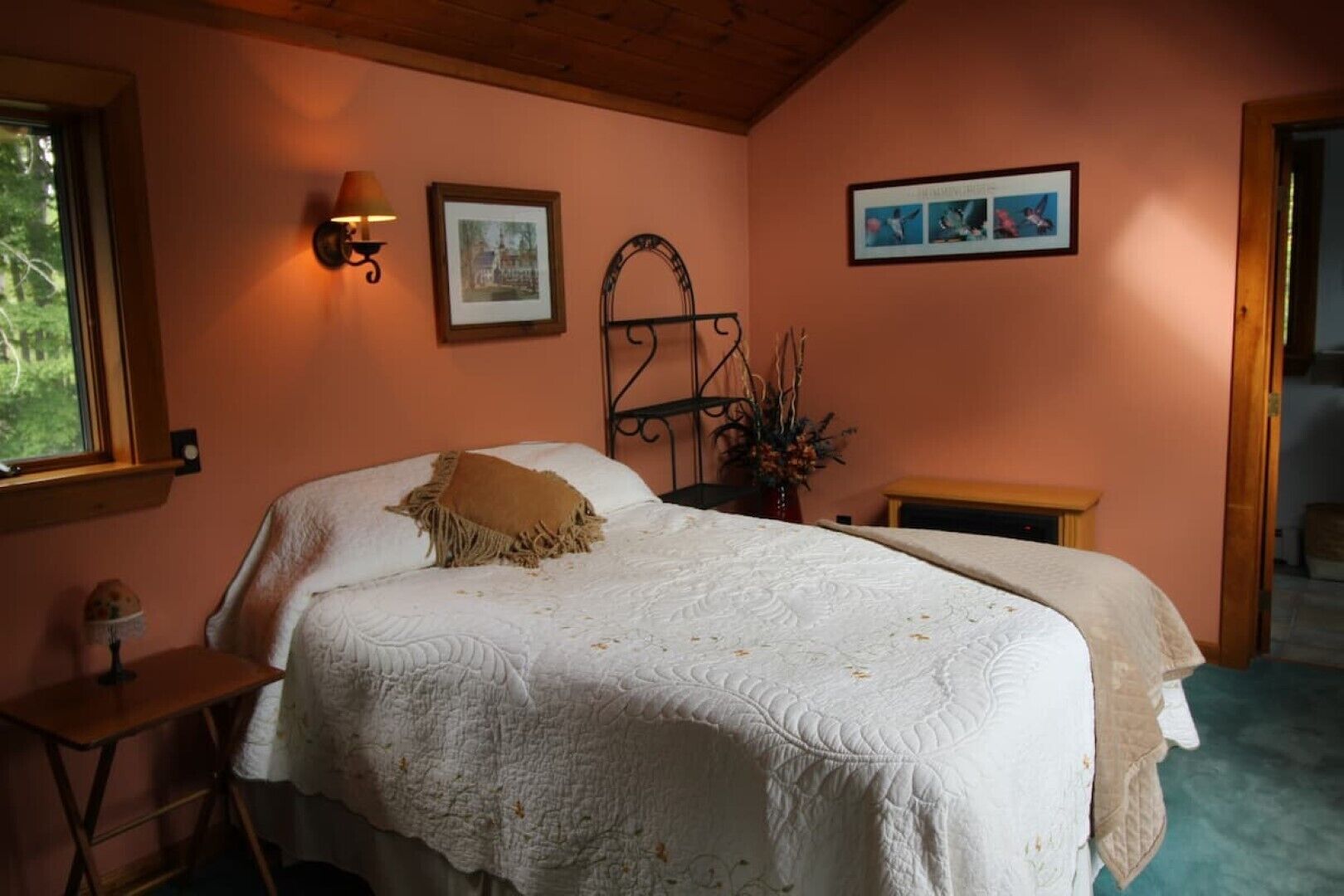 A bedroom with a large bed, a bedside table, a lamp, and framed pictures on the wall.