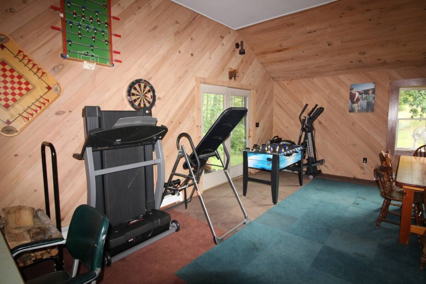 A room with a foosball table, dartboard, and exercise equipment.