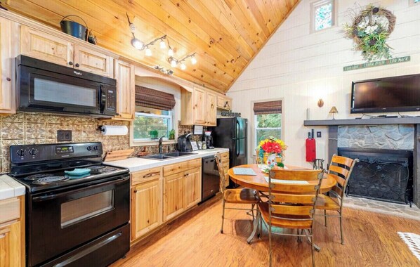 Enjoy cooking in this well-equipped kitchen with a microwave, stove, and dishwasher. The space features a dining area with a round table and chairs.