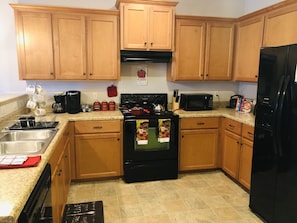 Kitchen equipped with a stove, refrigerator, and microwave, along with a sink and basic appliances.