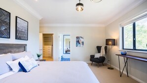 Ein Schlafzimmer mit einem großen Bett, einem Sessel, einem Tisch und einem Fenster.
