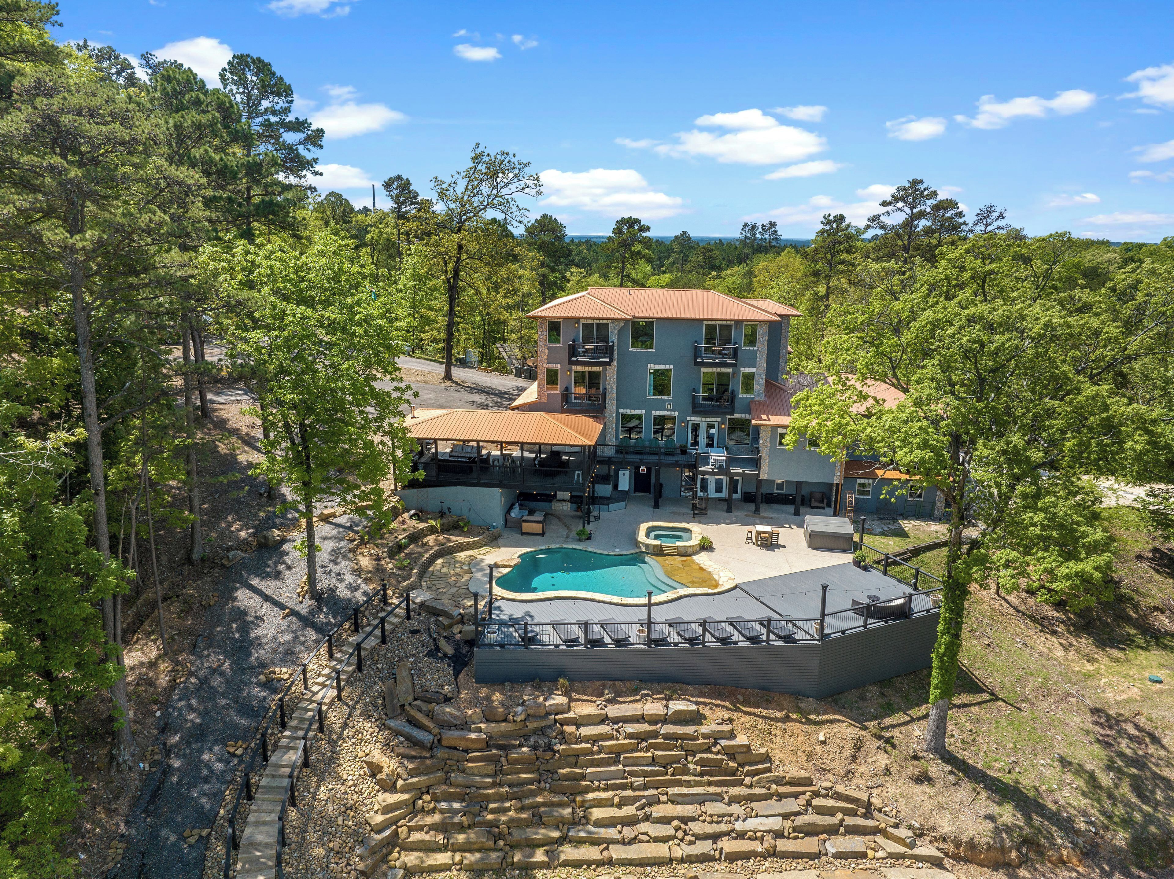 A multi-story building with a pool, outdoor seating, and a stone fire pit area.