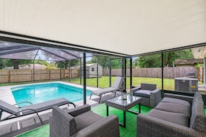A covered patio area with a pool, outdoor furniture, and a view of the backyard.