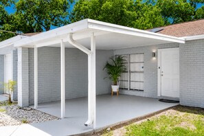 A modern house with a covered patio, white brick walls, and a large window. - Screened Heated Pool, Sleeps 12 | Game Room, 10 Min to Hard Rock Casino (Seffner)