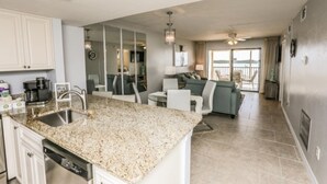 A modern kitchen with granite countertops, white cabinetry, and a built-in dishwasher.
