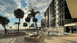 A rooftop pool area with palm trees, a swimming pool, and a view of the ocean.