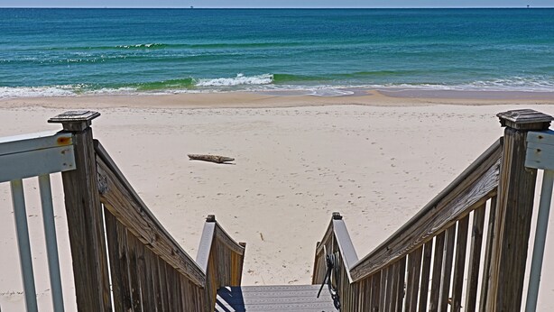 A wooden staircase leading to a beach with a clear view of the ocean. - Cute Bungalow w/small pool!
Absolutely Beach Front! (Gulf Shores)