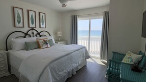 A bedroom with a bed, a nightstand, a chair, a ceiling fan, and a view of the beach. - Cute Bungalow w/small pool!
Absolutely Beach Front! (Gulf Shores)