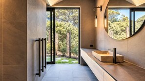 A modern bathroom with a large window, a built-in sink, and a mirror. - Mawhiti - Architecture & Beach Access Near Oneroa (Waiheke Island)