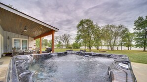 A hot tub in a backyard with a covered patio and outdoor furniture. - Hot Tub, Game Room & More! Lakefront Home in Afton (Afton)