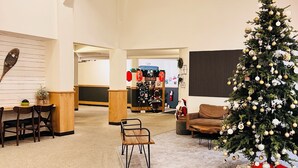 Un hall d’hôtel spacieux, décoré d’un sapin de Noël, avec des meubles en bois et un comptoir d’accueil en arrière-plan.