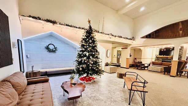 Un vaste espace de vie agrémenté d’un grand sapin de Noël, d’une cheminée et d’un coin salon confortable.