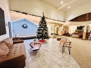 Un amplio salón con un gran árbol de Navidad, una chimenea y un acogedor conjunto de asientos.