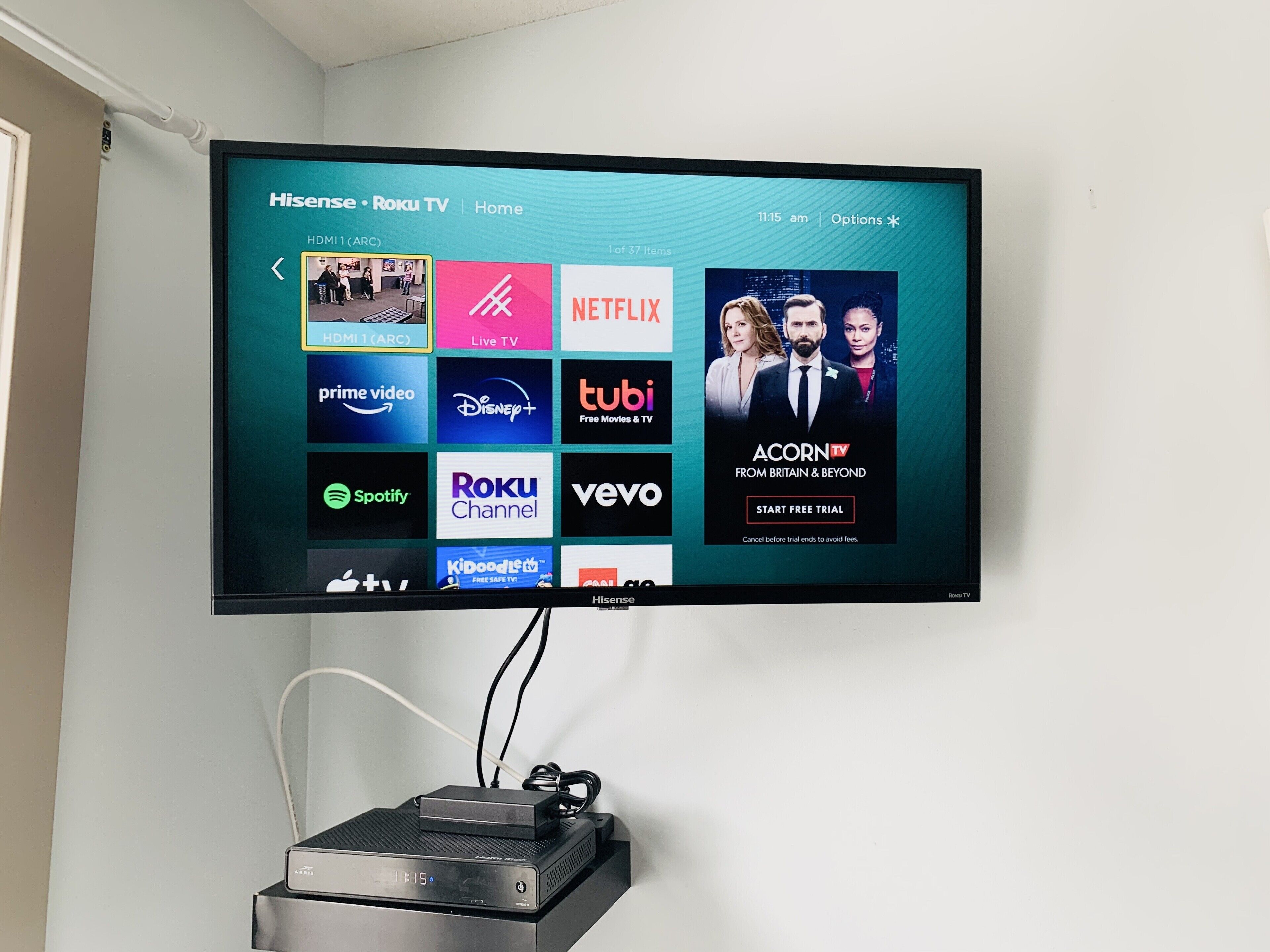 A flat-screen TV mounted on a wall displaying a streaming service interface with various app icons.