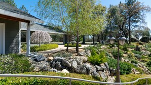 A landscaped garden with a house, stone pathway, and outdoor lighting.